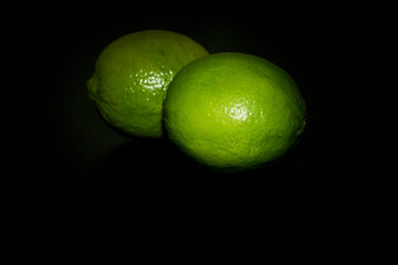 Green limes close up in darkness.