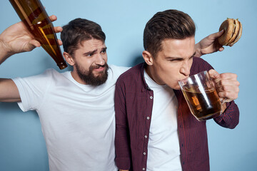 Two cheerful drunk friends drinking beer lifestyle emotions on a blue background