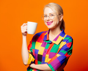 Style blonde in 90s shirt and glasses with a cup