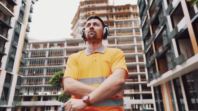 Construction worker with ear muff working at construction site. Worker puts on ear defenders to protect against sound. Taking care of health, safety at work. Earplugs. Too loud sound, hearing damage.