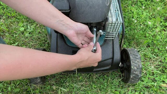 Changing replacing lawn mower spark plug, landscape equipment repair service, process of unscrewing spark plug