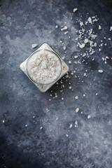 Sea salt in a glass jar on a gray background.