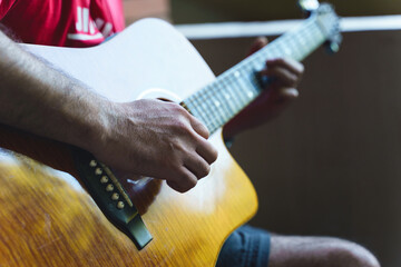 Detail of midsection of man with acoustical guitar focus on hand unknown person playing - shallow depth of field music instrument leisure concept