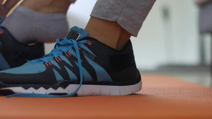 Young woman tying her shoelaces in her bedroom, preparing for workout, indoor home exercise concept, close up image - Powered by Adobe