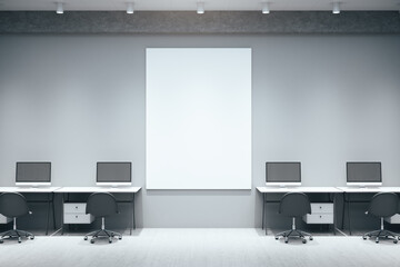 Workplace room with computers and empty vertical poster on gray wall