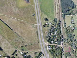 Vista aérea a vuelo de pájaro,  de una autopista de cuatro carriles, con algunas casas.