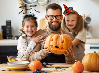 happy family   father and children prepare for Halloween by carving pumpkins at home in kitchen.