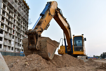 Excavator on earthmoving at construction site. Backhoe dig pit foundation.  Construction machinery...