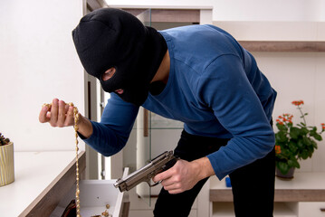 Male robber stealing valuable things from the house