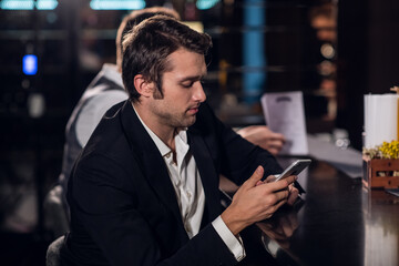 a young man reads a message on his phone, sits in a bar.