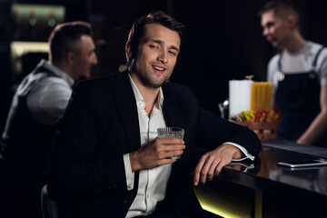 portrait of a young man in a shirt and jacket at the bar with a cocktail in his hands.