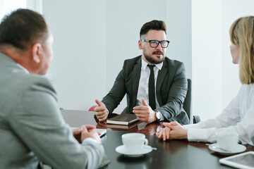 Confident businessman in formalwear consulting young colleague at meeting