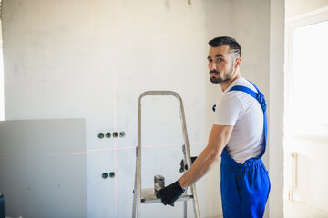 A handyman moves an aluminum step ladder around the room