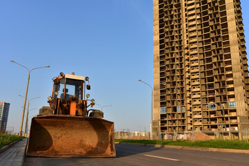 Wheel loader with a bucket on a street in the city during the construction of the road. Construction site with heavy machinery for road work. Front end loader on road building. Civil engineering