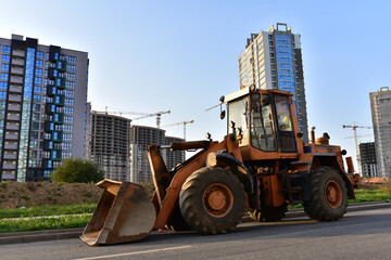 Wheel loader with a bucket on a street in the city during the construction of the road....