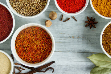 Round bowl with spice on a wooden table - saffron,  vanilla,  sumac and star anise. Fragrant seasonings.