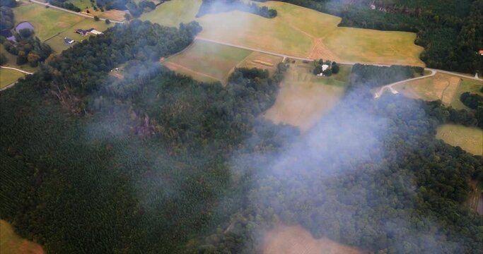 Smoke From Fire in Snow Camp, North Carolina. The view from the airplane shows a low pass through smoke from a fire on the ground. Open fields, roads and some houses are seen in this colorful footage.