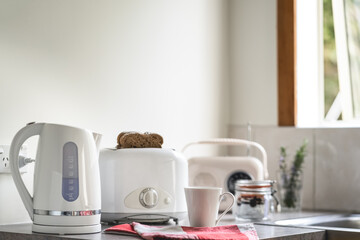 Breakfast table with white appliances, electric kettle toaster, mug and vintage radio