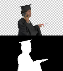 African American female student in graduation robe talking on th