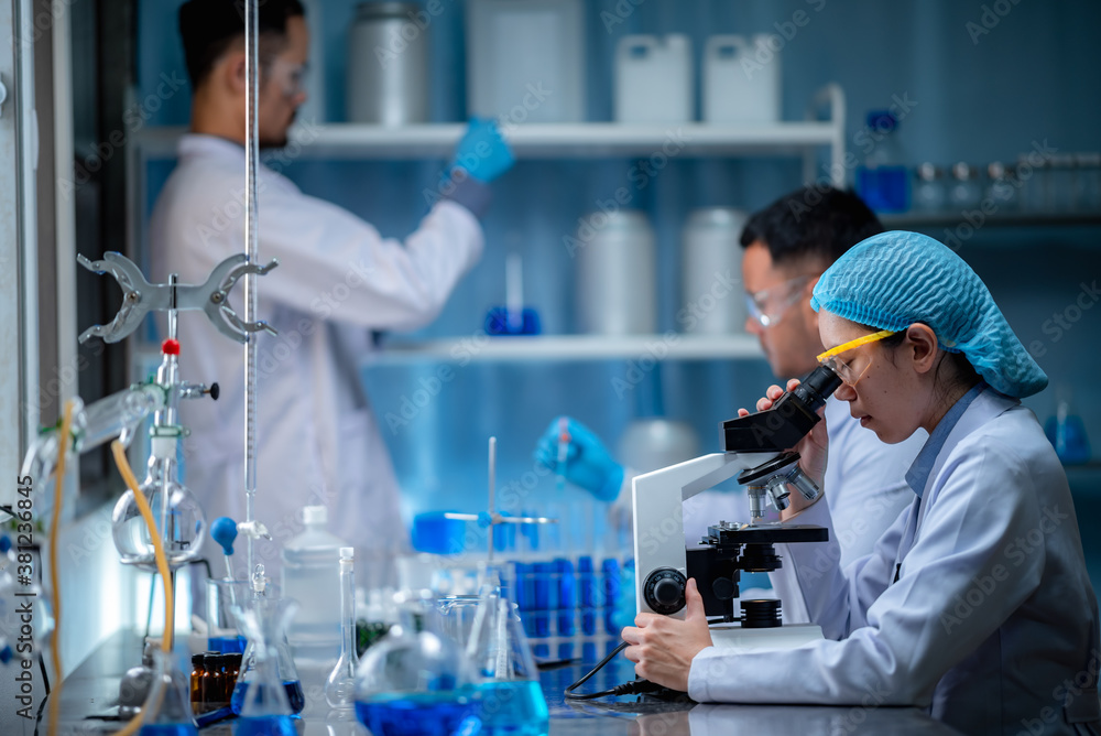 Wall mural young scientist looking through a microscope in a laboratory. young scientist doing some research.