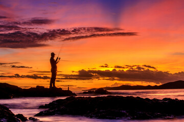Silhouette of motion Blur Fisherman during sunset with colorful sky burst in background