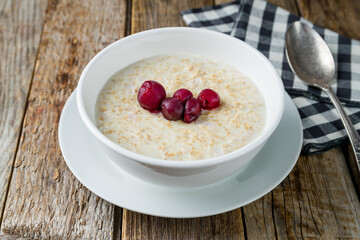 Oatmeal with berries on white plate on old wooden table