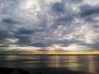 Beautiful cloudy sunset in the Caribbean Sea, the sunset produces yellow and orange colors, cargo ships are seen on the horizon.