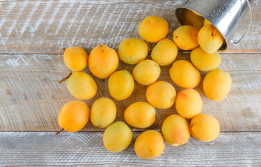 Scattered apricots from mini bucket on a wooden background. flat lay.