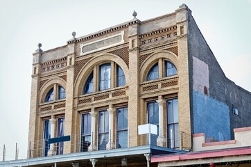Historic building in The Strand, downtown Galveston Island, Texas with arches, tall windows, balcony, stone facade