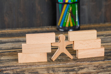 Back to school concept with wooden blocks, human figure, pencils on wooden background high angle view.