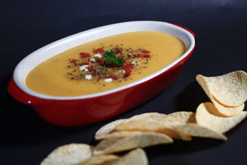 Pumpkin and carrot soup with cream and parsley and potato chips on dark background. bokeh shot.