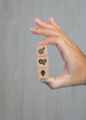 Business concept on grey background side view. hand holding wooden cubes with icons.