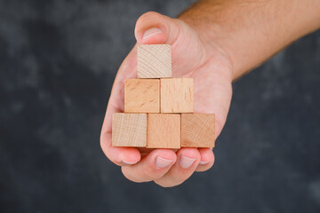 Business concept on grungy grey background side view. hand holding wooden blocks.