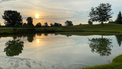 early morning sun golf course pond cloud tree reflections