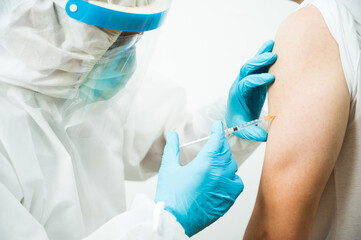 Doctor injecting vaccine covid-19 to young man. Vaccination concept.