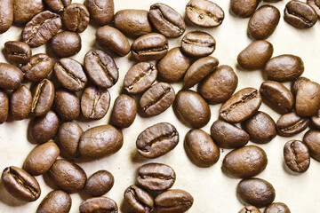 Coffee seeds on vintage paper background. Coffee beans texture. Warm color brown roasted grain.