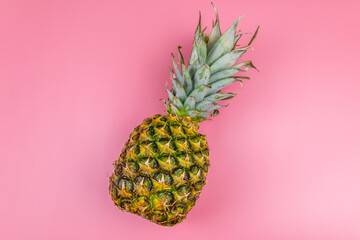 One whole pineapple on pink background. Top view