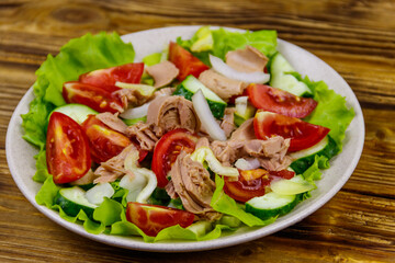 Tasty tuna salad with lettuce and fresh vegetables on wooden table