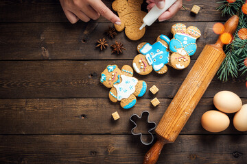 Female hands decorate Christmas cookies on wooden background top view