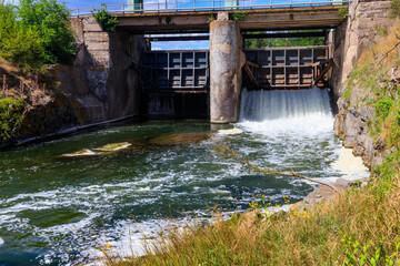 Flowing water with water spray from the open sluice gates of a small dam