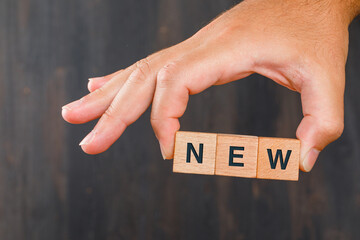 Business idea concept on wooden background side view. hand holding wooden cubes.