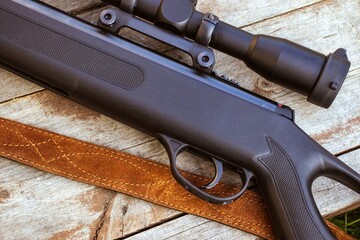 Black rifle with a telescopic sight on a wooden background.