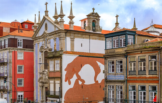 Porto, Portugal - May 30, 2018: Facades of traditional houses and Parish Church of St. Nicholas with ornate Portuguese azulejo tiles in Ribeira