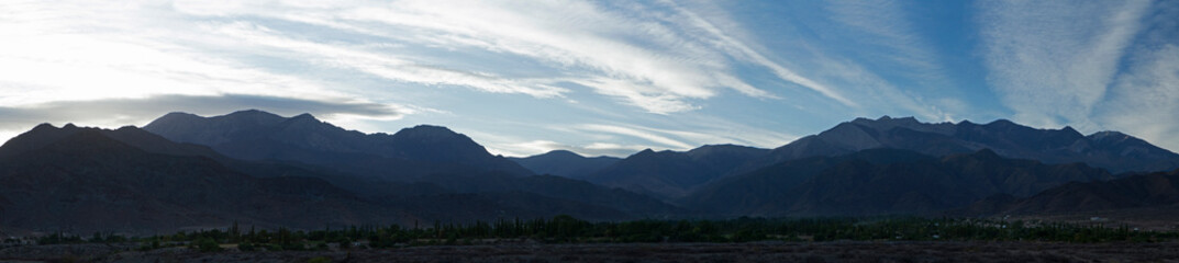 Fototapeta na wymiar The mountains at sunrise. Beautiful panorama view of the Andes mountain range at dawn. The desert and mountains silhouette with blue colors.