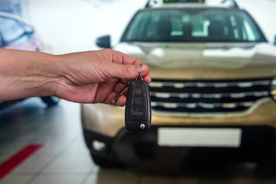 Male hand with car keys with auto on background