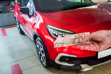 concept of buying a new car. male hand holds a euro for a successful deal