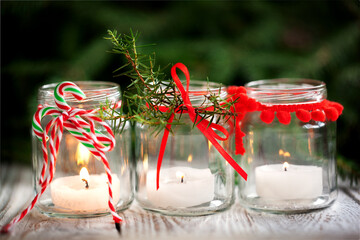 Cozy handmade holiday home decor. Christmas decoration with candles in glass jars decorated red...