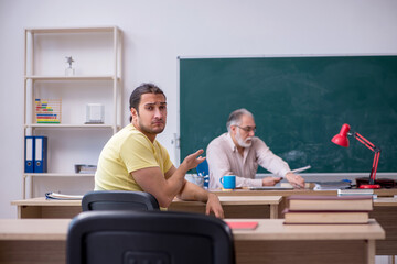 Old teacher and young male student in the classroom