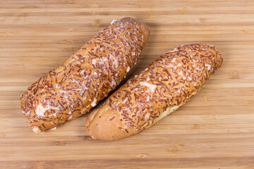 Buns covered with grated melted cheese on a cutting board