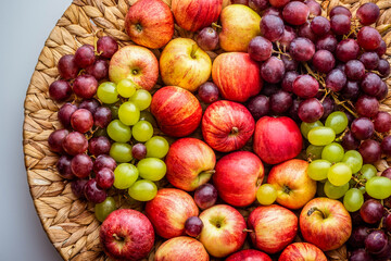 Naklejka na ściany i meble Red apples and grapes on a wicker dish. 